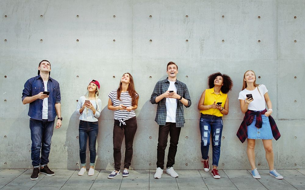 Group of young adults outdoors using smartphones looking up
