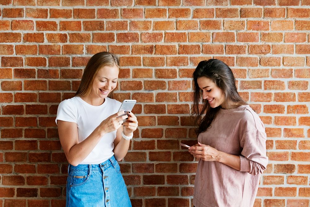 Happy female friends using smartphones