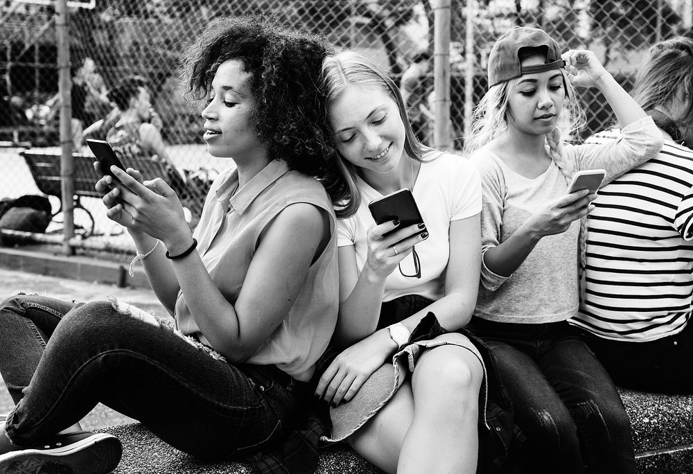 Friends in the park using smartphones and chilling