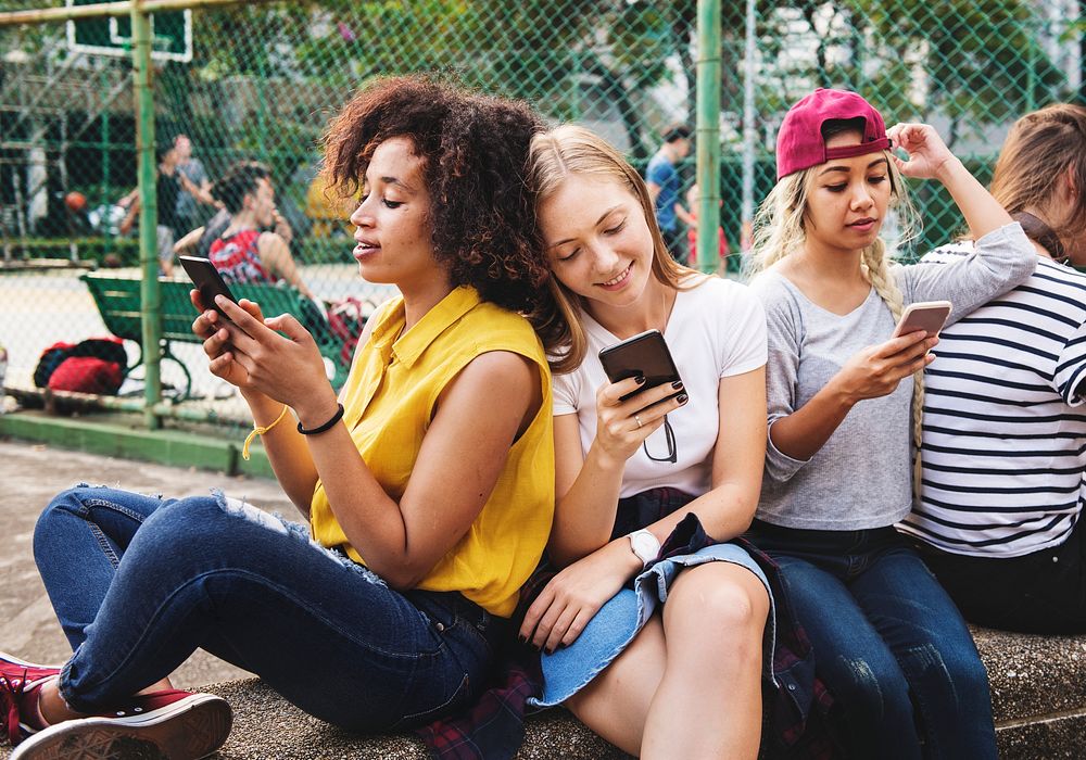 Young adult friends using smartphones together outdoors youth culture concept