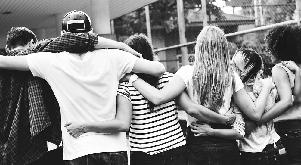 Smiling happy young adult friends arms around shoulder outdoors friendship and connection concept