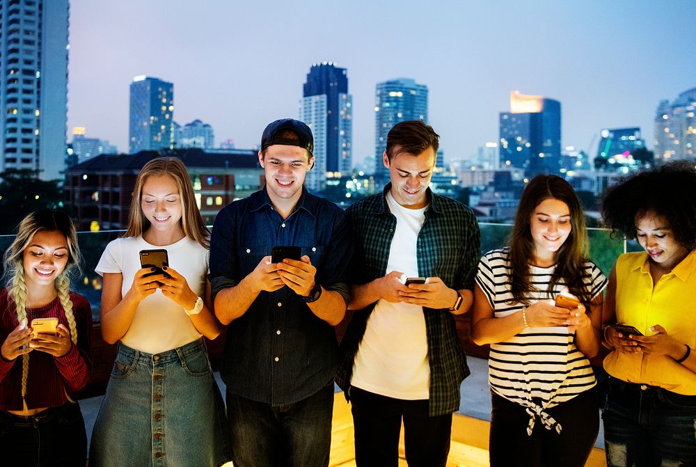 Happy group of young adults using smartphones in the cityscape