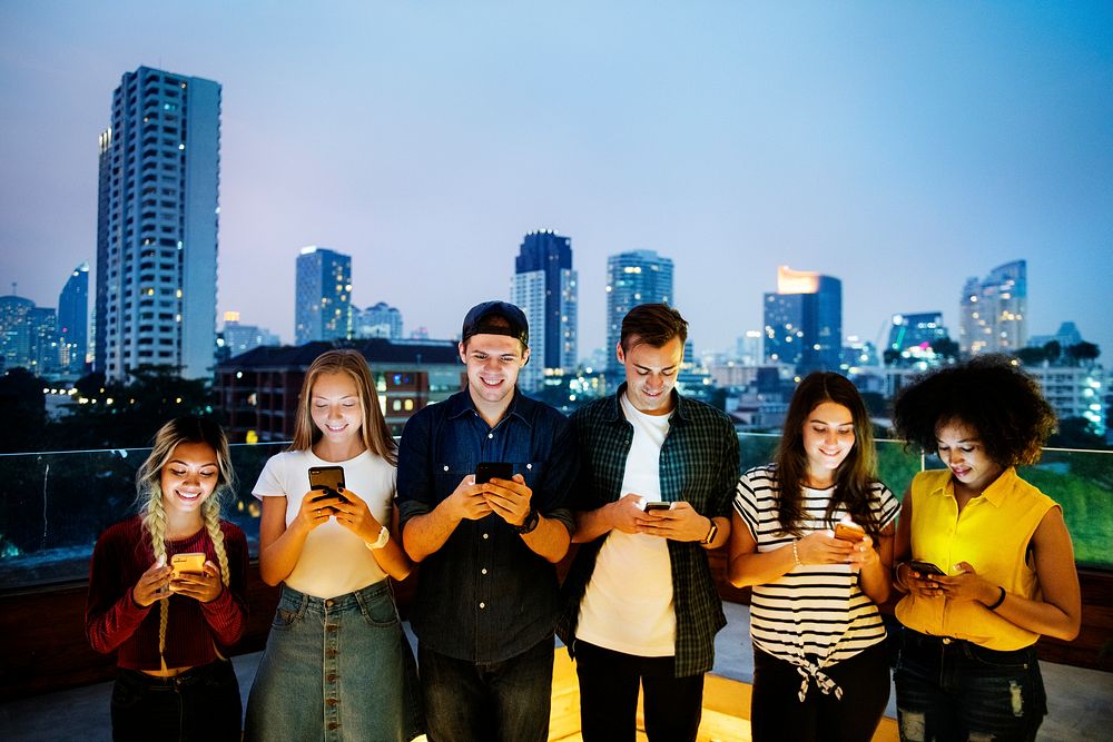 Happy group of young adults using smartphones in the cityscape