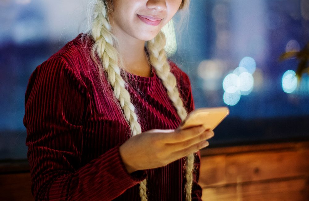 Smiling young woman using a smartphone in the evening cityscape