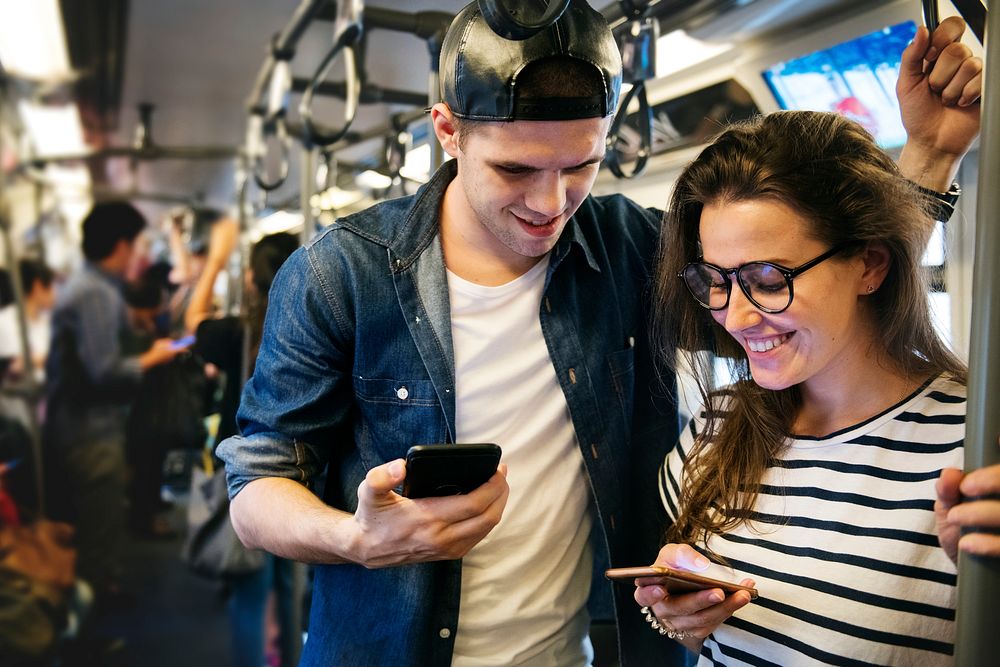 Cute couple using smartphones on the subway