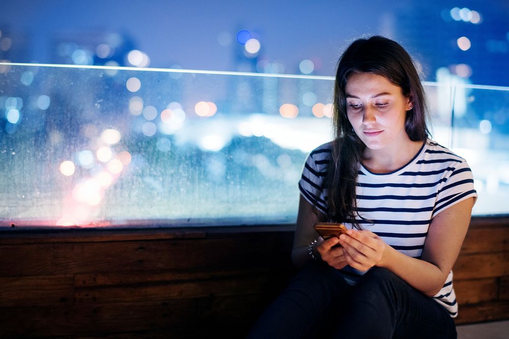 Young woman using a smartphone in the evening cityscape