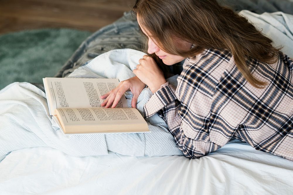 Caucasian woman reading book in bed