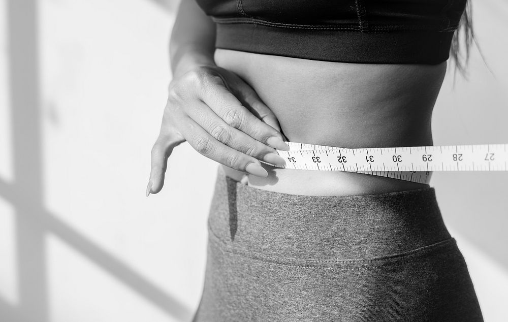 Asian woman measuring waist size
