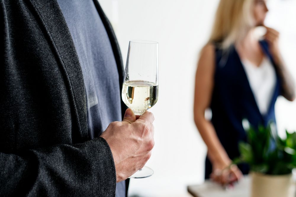 Closeup of man holding white wine glass