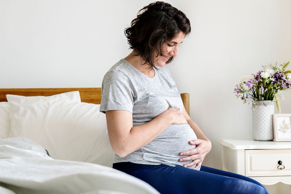 Pregnant woman sitting on the bed