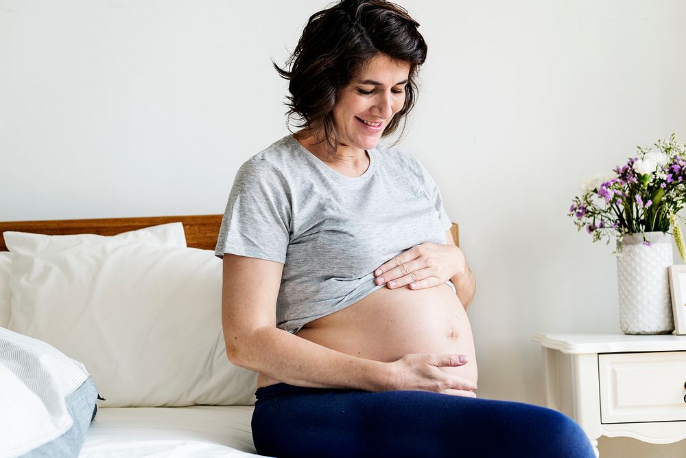 Pregnant woman sitting on the bed