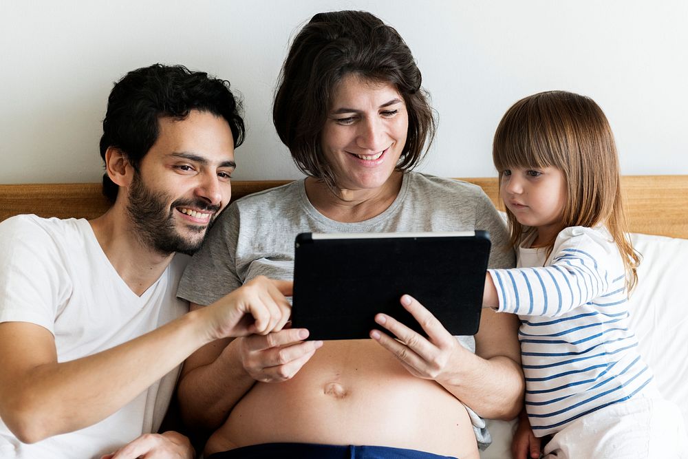 Pregnant family spending time together using a digital tablet