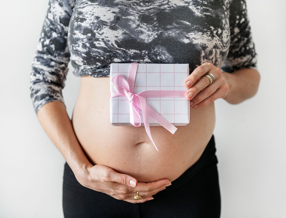 Pregnant woman holding a gift box in front of her baby bump