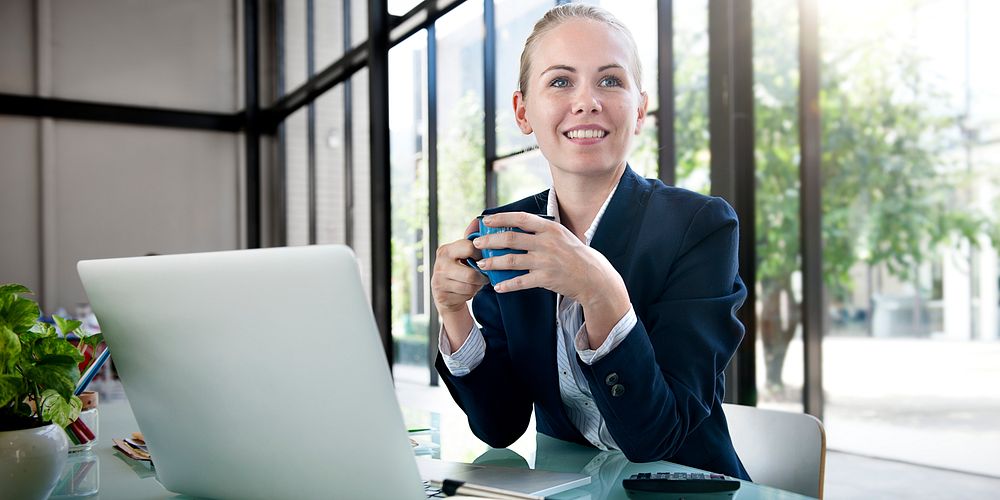 Young woman drinking coffee at her workstation