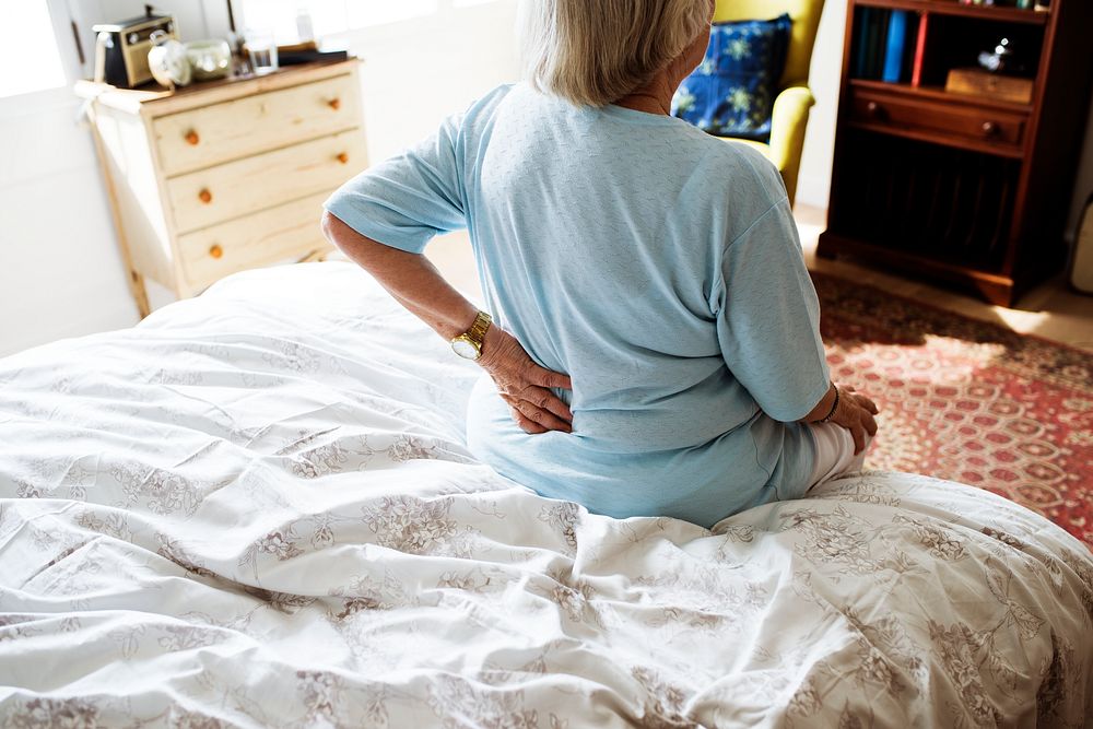 Senior woman sitting on the bed in pain