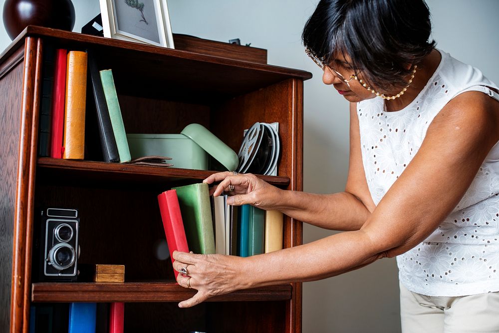 Senior woman cleaning the bookshelf