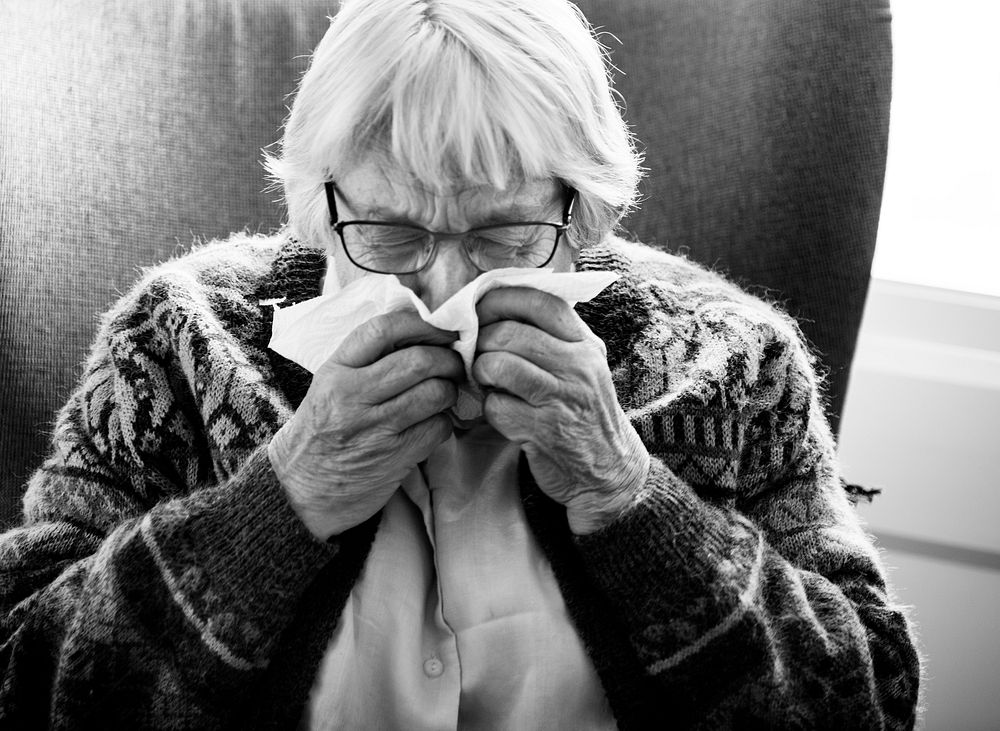 Black and white photo of senior woman sneezing