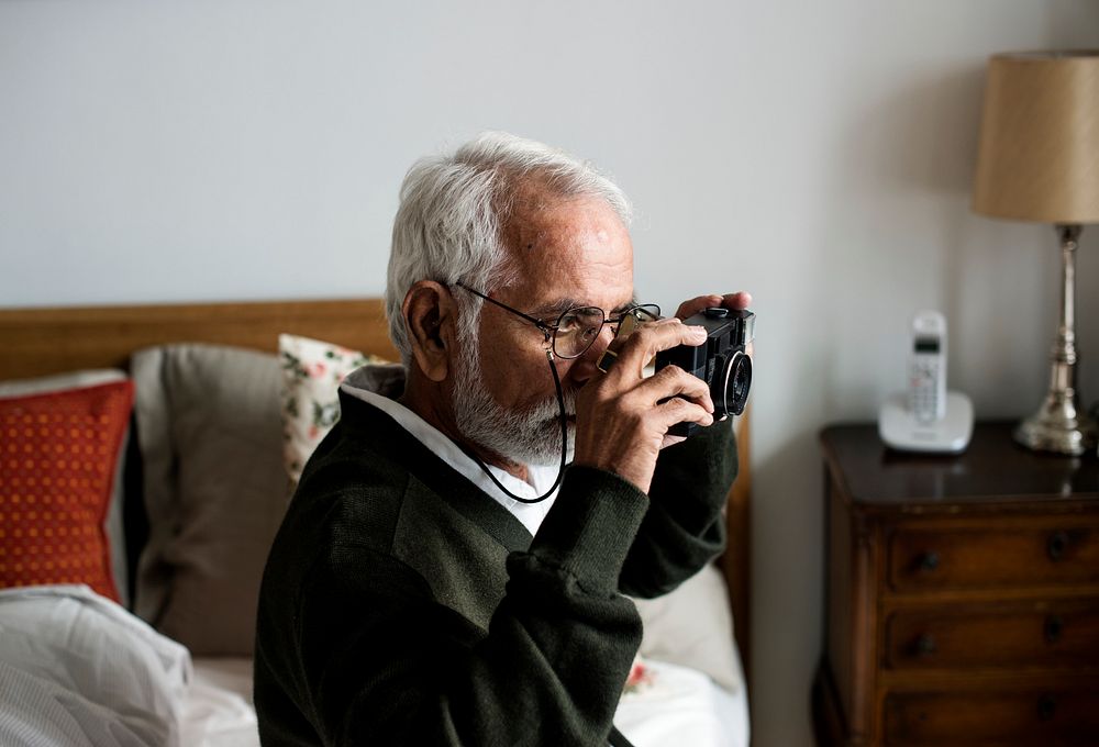 An elderly Indian man at the retirement house taking a photo