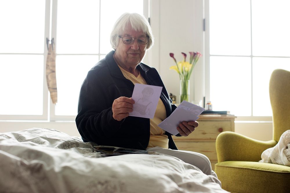Senior woman sitting on the bed and looking at photos