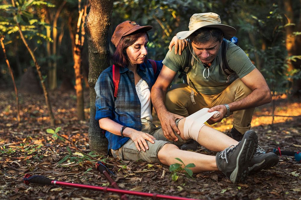 Man putting bandage on his partner's knee in the jungle