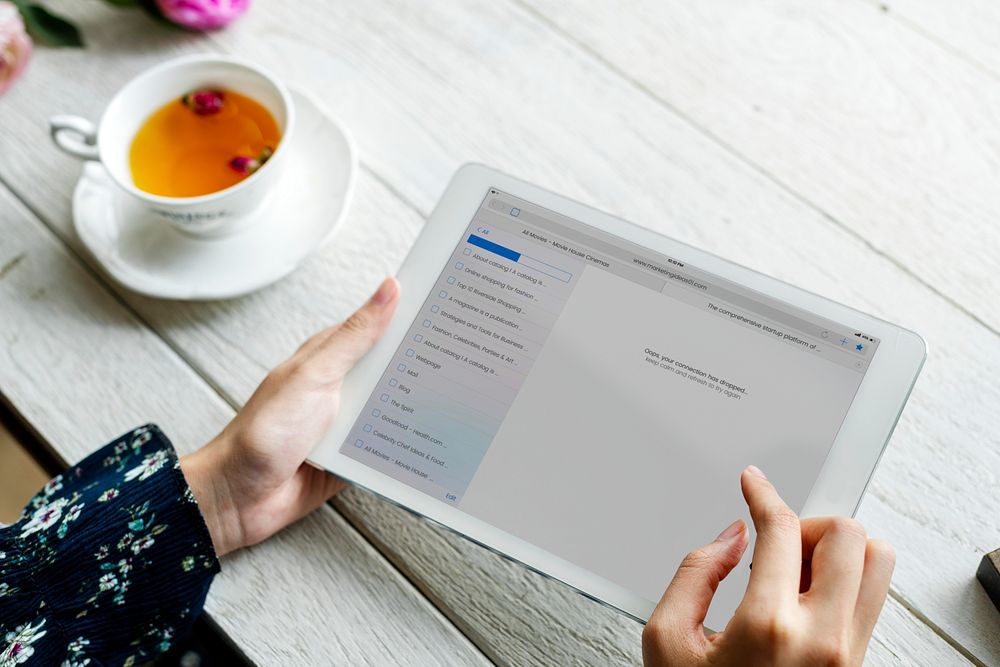 Aerial view of woman using digital tablet and a cup of hot tea