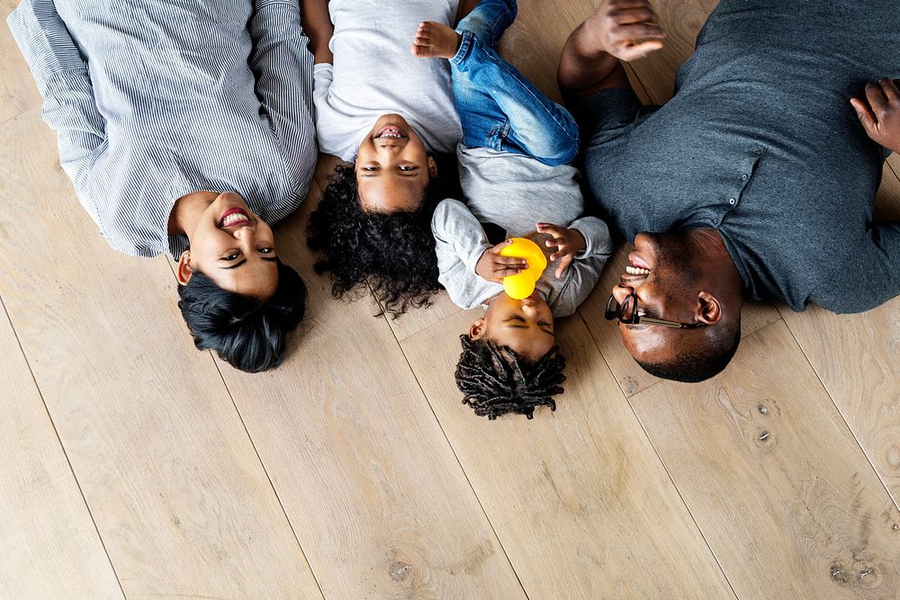 Black family lying on wooden floor design space