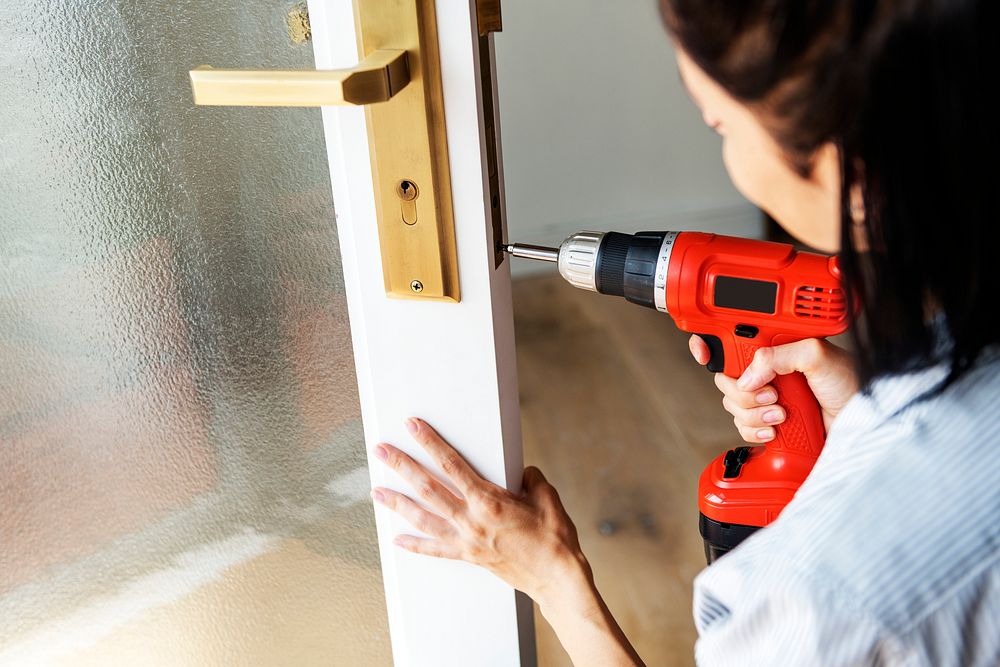 Woman using electronic drill install door