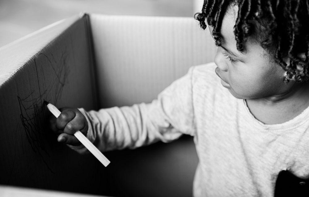 Young black boy drawing in a box