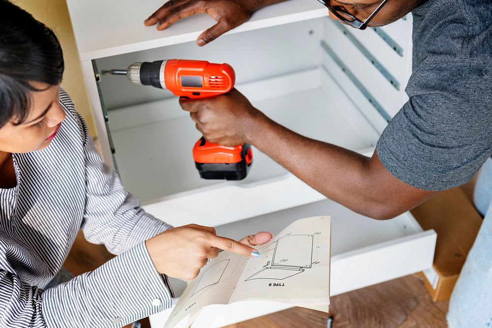 Man using electronic drill install cabinet