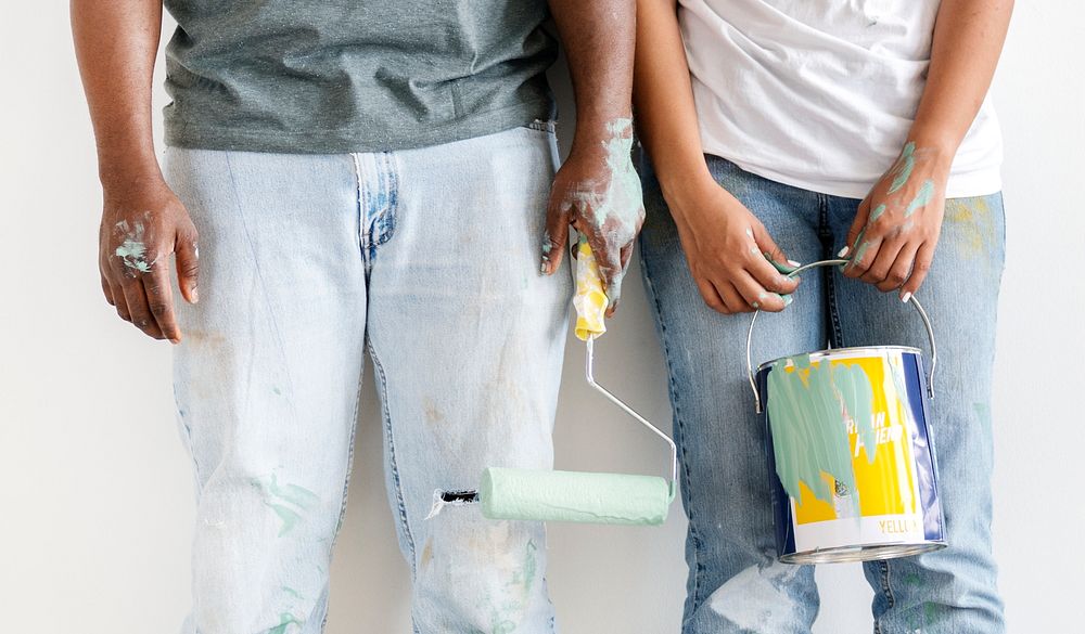 Happy couple painting house wall for interior design
