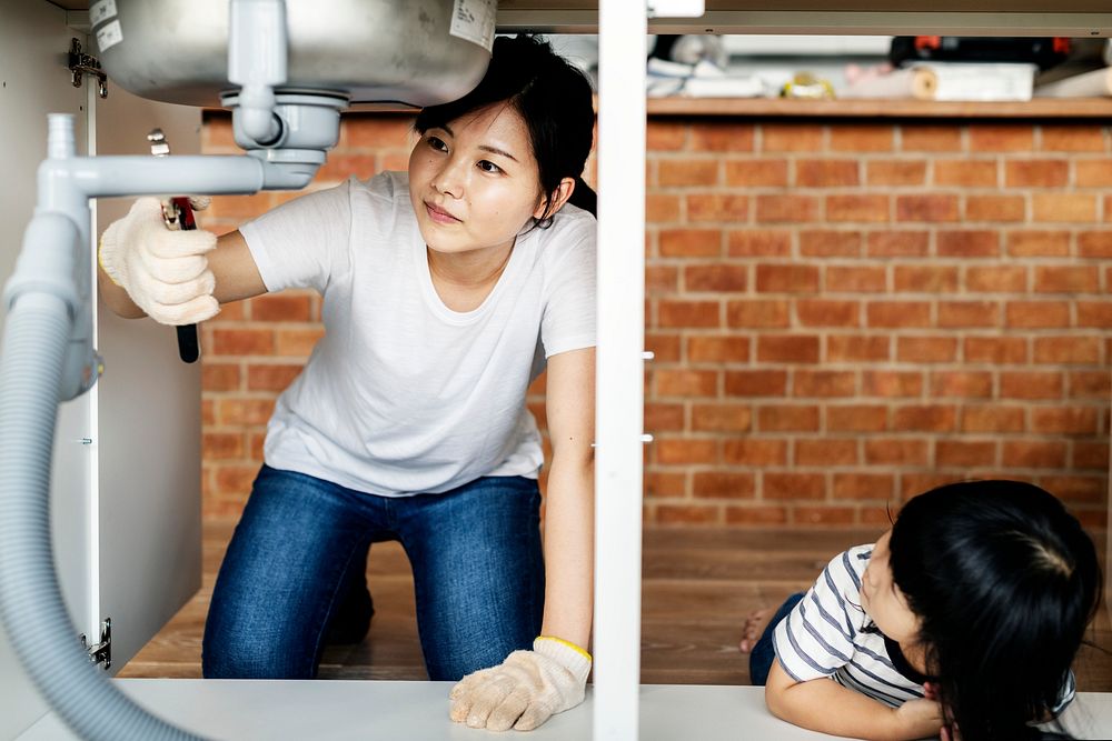 Asian family fixing kitchen sink