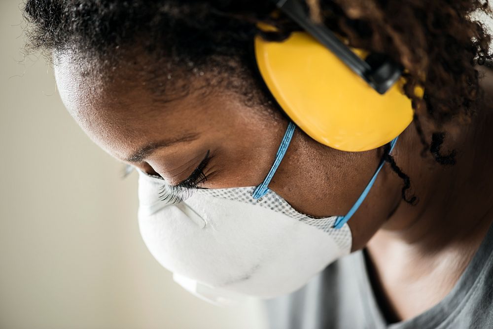 Black woman wearing ear protection and mask to work