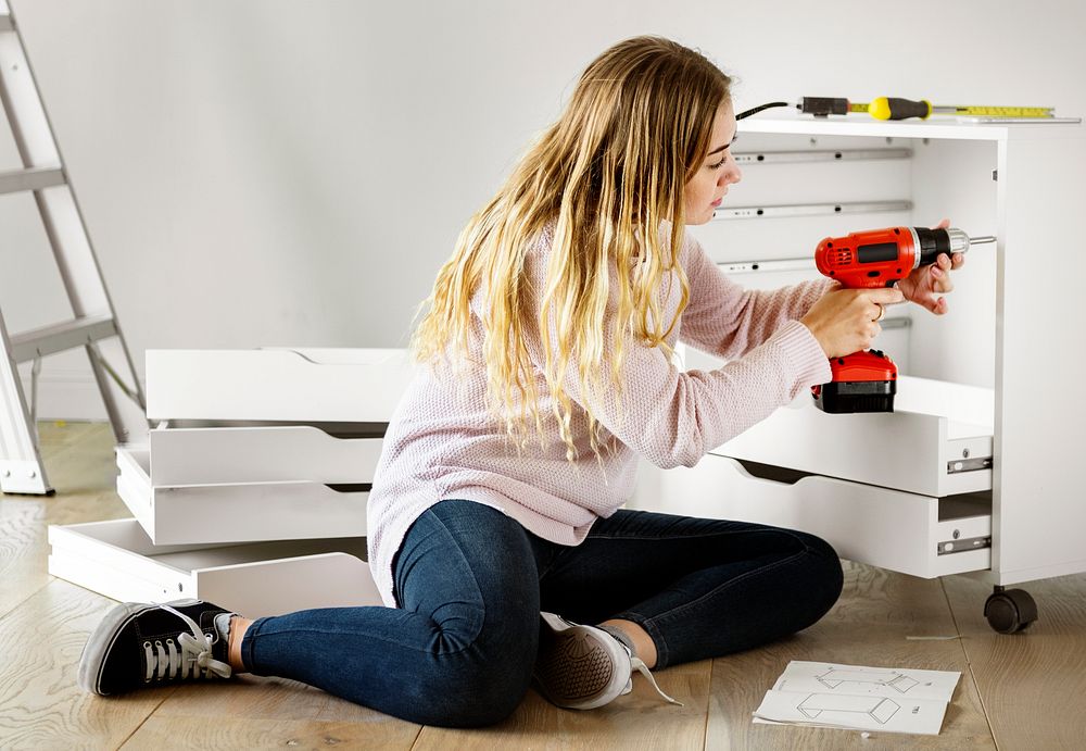 Woman using electronic drill install cabinet
