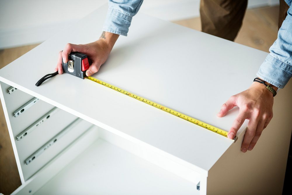 Man measuring the cabinet with measurement tape