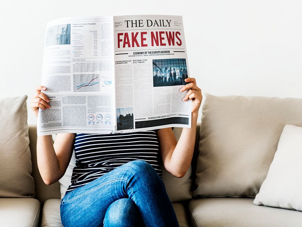 Woman reading newspaper with fake news