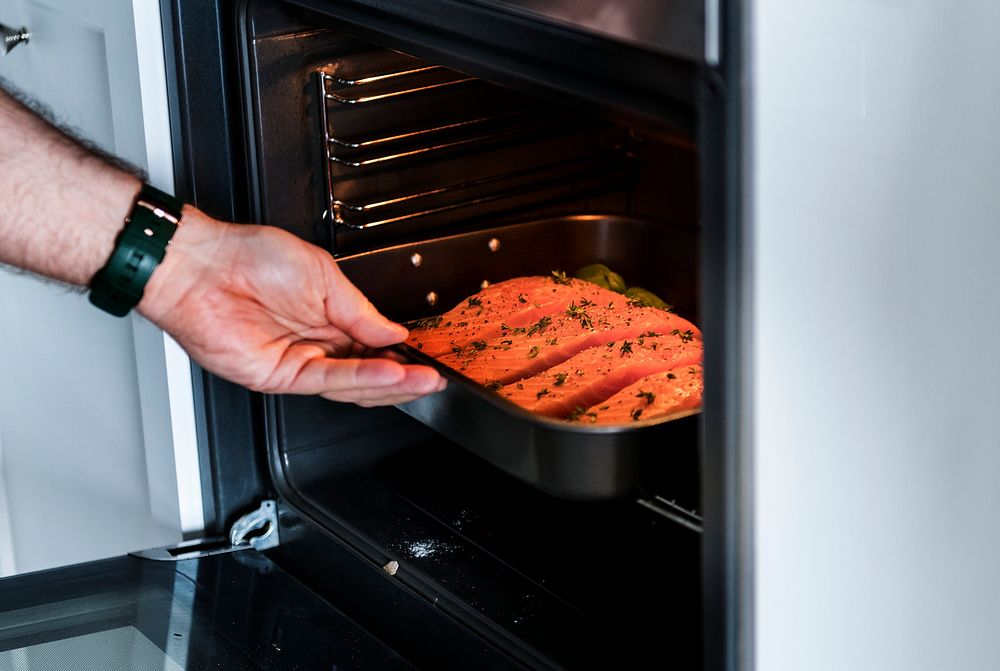 Man putting raw salmon steak into oven