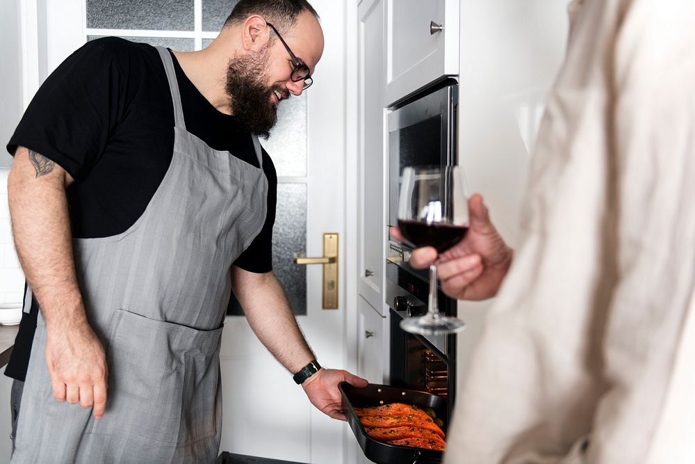 Man putting raw salmon steak into oven