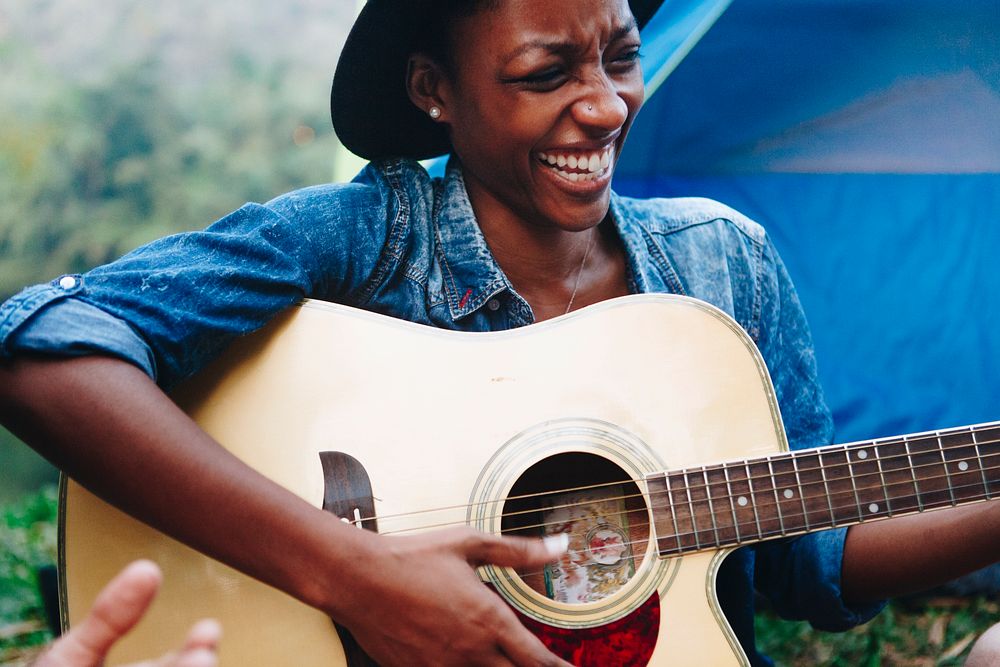African American woman playing a guitar at a campsite