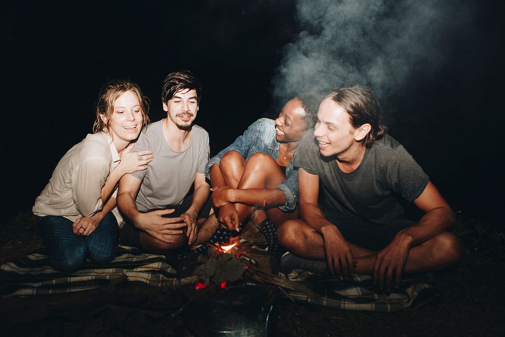 Group of friends sitting around a bonfire at a campsite