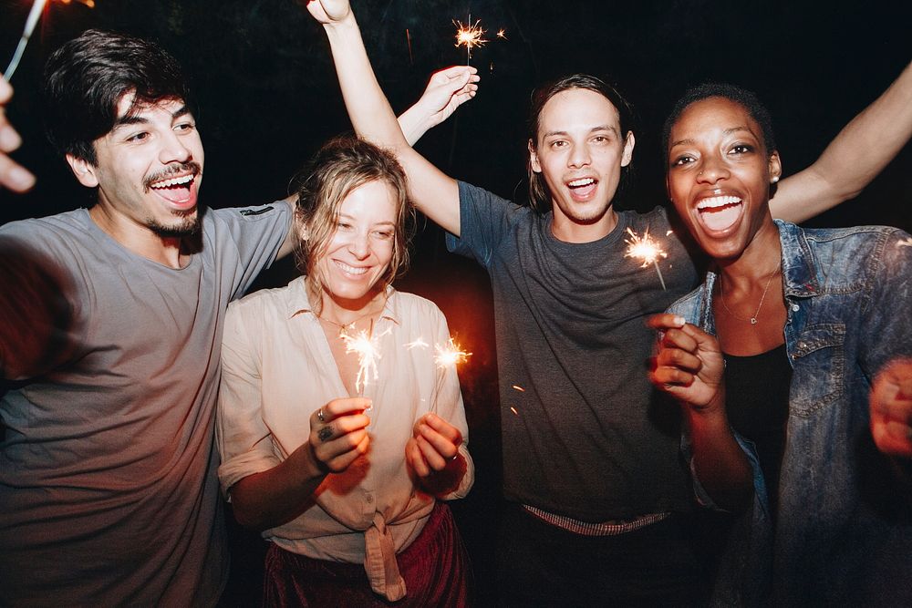 Mixed race friends playing with sparklers celebration and festive party concept