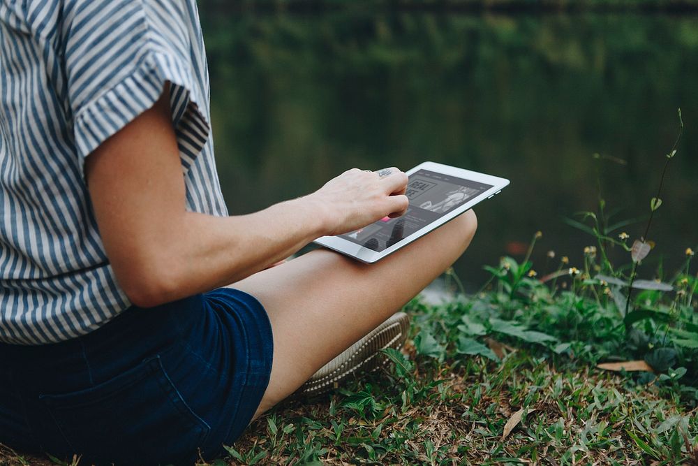 Woman alone in nature using a digital tablet with entertainment application on the screen internet connection and leisure…