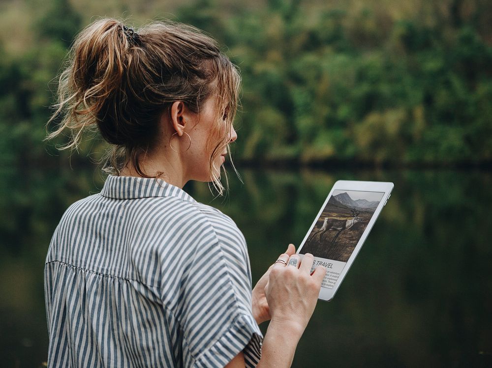 Woman alone in nature using a digital tablet internet connection and travel concept