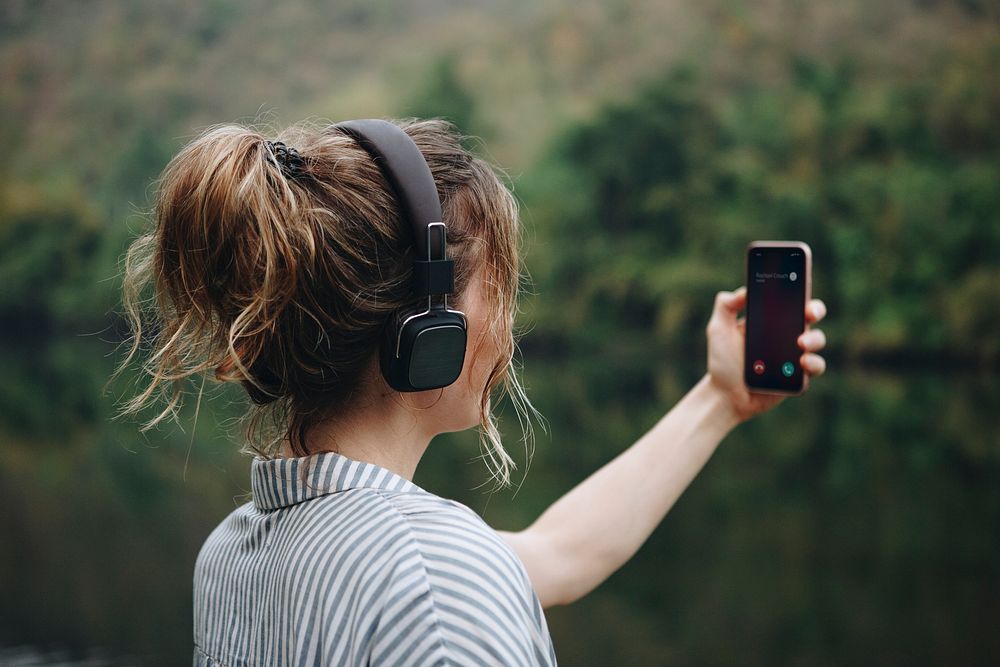 Woman alone in nature listening to music with headphones and a smartphone music and relaxation concept