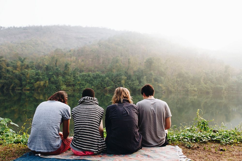 Group of friends relaxing by a lake in the morning