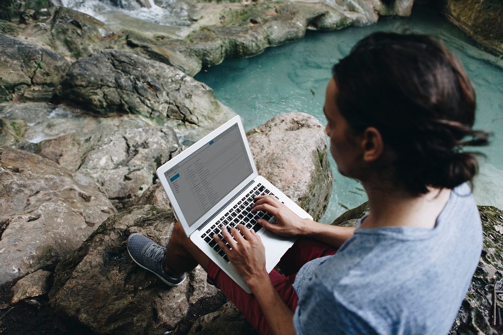 White man using computer laptop at waterfall
