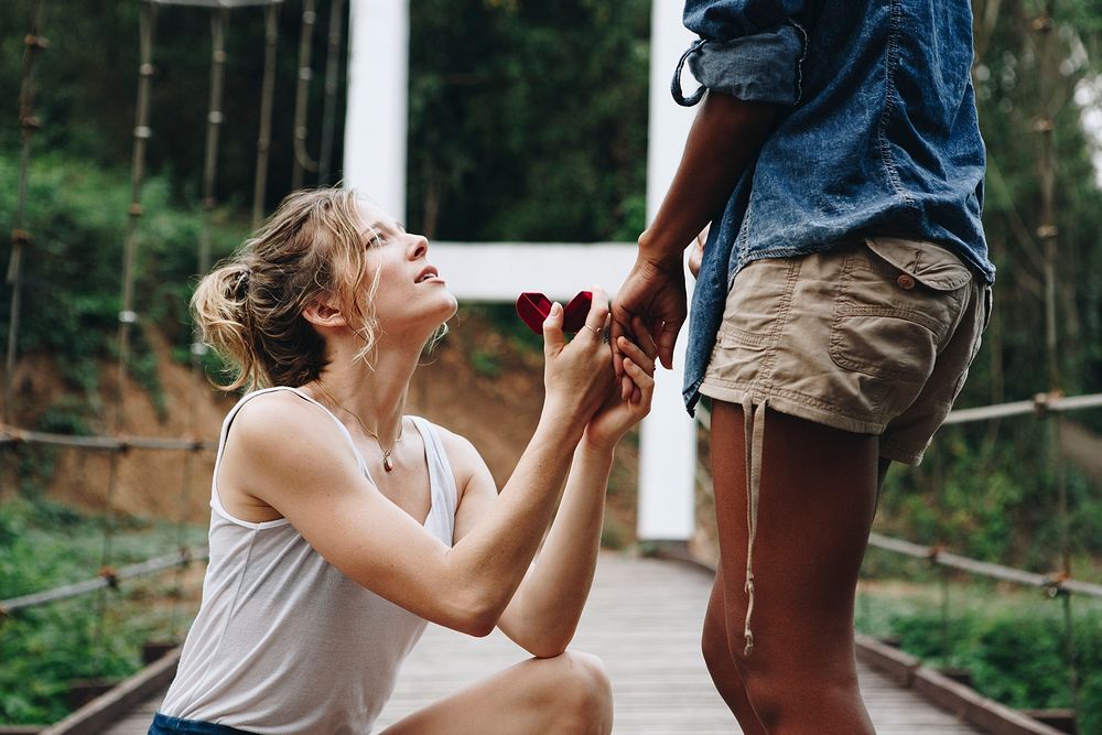 Woman proposing to her happy girlfriend outdoors love and marriage concept
