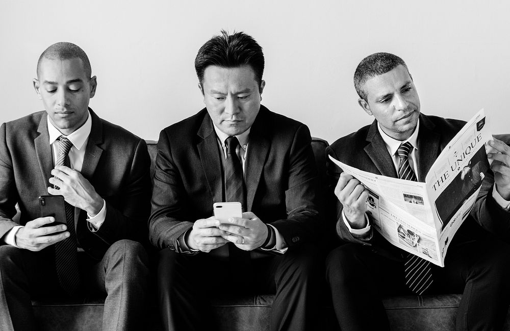 Businessmen working on phone and reading newspaper