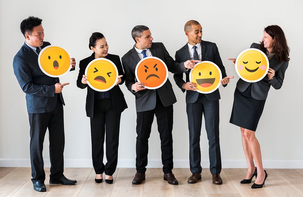 Business people standing and holding emoji icons