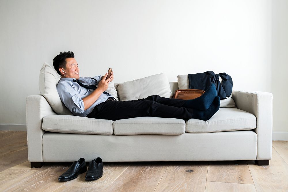 Asian businessman taking break laying on couch