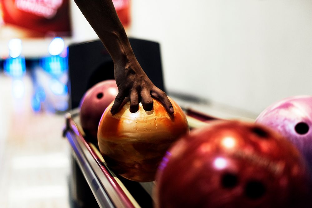 African American boy picking up a bowling ball hobby and leisure concept